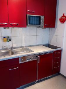 a red kitchen with a sink and a microwave at Fewo Therme im Oberharz in Altenau