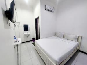 a white bedroom with a bed and a television at COZY STAY KUPANG in Kupang