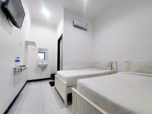 a white room with two beds and a tv at COZY STAY KUPANG in Kupang