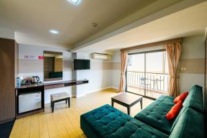 uma sala de estar com um sofá verde e uma cozinha em Scandia Beach Hotel em Praia de Jomtien