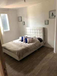 a bedroom with a white bed with blue pillows at Villa Agde très calme in Agde