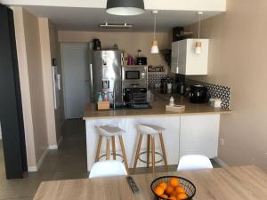 a kitchen with a counter with stools and a microwave at Villa Agde très calme in Agde