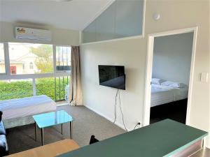 a room with two beds and a table and a tv at Ranfurly Evergreen Motel in Auckland