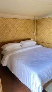 a large bed with white sheets and pillows at Deoja Forest Stay in Darjeeling