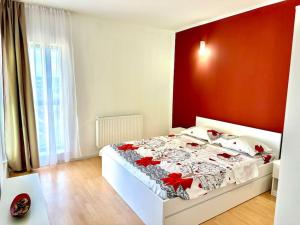 a bedroom with a white bed with a red wall at Apartament Novara 2 in Craiova