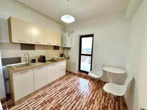 a kitchen with white cabinets and a wooden floor at Apartament Novara 2 in Craiova