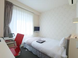 Habitación de hotel con cama y silla roja en Fukuyama Oriental Hotel en Fukuyama