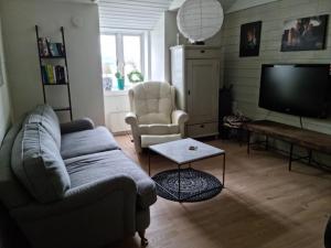 a living room with a couch and two chairs and a tv at Sjötomt i Mariefred in Mariefred