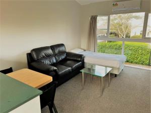 a living room with a leather couch and a table at Ranfurly Evergreen Motel in Auckland