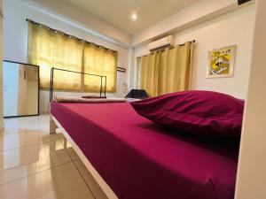Aekkalukthai Hostel Rayong في رايونغ: سرير وردي كبير في غرفة مع نافذة