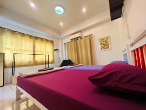 Aekkalukthai Hostel Rayong في رايونغ: سرير كبير في غرفة ذات بطانية وردية