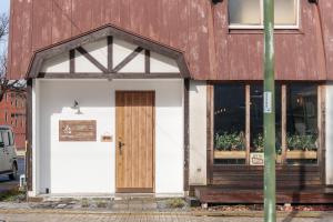 um edifício com uma porta de madeira e janelas em YUKARA LEAF LODGE em Nanae