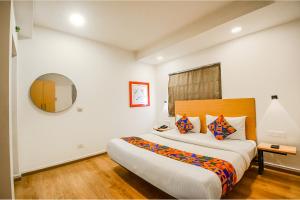 a bedroom with a large bed and a mirror at FabHotel Airport Green Arcade in Kolkata