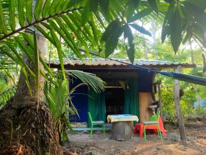 une petite maison avec des chaises colorées devant elle dans l'établissement Jungle Tent 3x3, Latino Glamping & Tours, Paquera, à Paquera