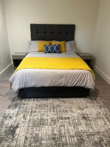 a bed with yellow and blue pillows and a rug at Modern 1 bedroom flat high street, great location in Hemel Hempstead