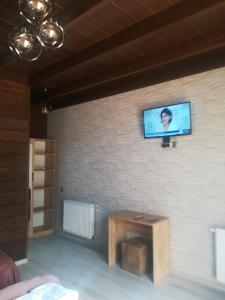 een televisie op een bakstenen muur met een tafel in een kamer bij Come & Rest in Kazbegi