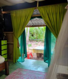 a bedroom with green curtains and a table at Jungle Tent 3x3, Latino Glamping & Tours, Paquera in Paquera