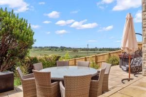 un patio con mesa, sillas y sombrilla en Bay View Luxury Stays - Southdown en Overcombe