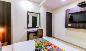 a room with a bed and a desk and a television at FabHotel Galaxy Suite in Mumbai