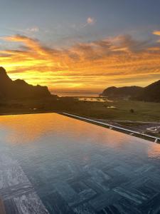 a large swimming pool with a sunset in the background at The Eden Cat Ba in Cat Ba