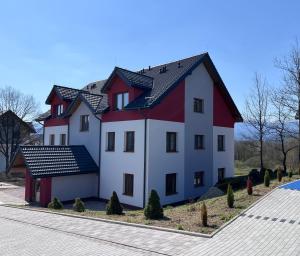 耶萊尼亞古拉的住宿－Kolorowe Cieplice - Apartamenty z widokiem na Karkonosze，黑色屋顶的白色和红色大房子