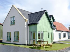 uma casa verde e branca com uma mesa de piquenique em Strathspey em Grange