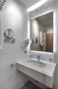 a white bathroom with a sink and a mirror at City Park Inn - Art Gallery in Plovdiv