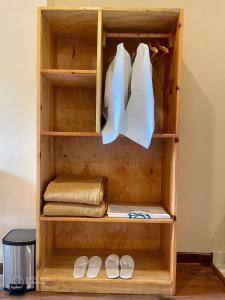 ein Holzschrank mit weißen Kleidern und Schuhen in der Unterkunft Shomo Chuki Resort in Paro