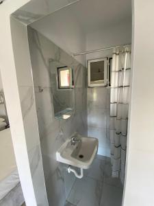 een witte badkamer met een wastafel en een spiegel bij Cathrin’s villas and apartments in Zverneci
