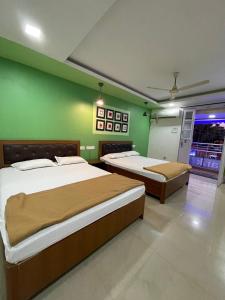 two beds in a room with green walls at Hotel Sai Advika in Mapusa