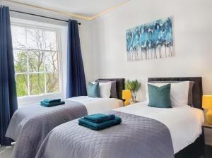a bedroom with two beds with blue pillows on them at The Yorkshire Hosts - Langton Lodge Apt.9 in Wakefield