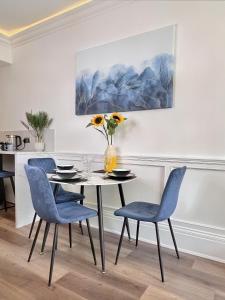 a dining room table with blue chairs and a vase of flowers at The Yorkshire Hosts - Langton Lodge Apt.9 in Wakefield