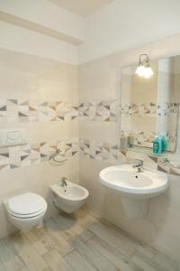 a bathroom with a sink and a toilet and a mirror at MARIS Apartments & Bedrooms in Alghero
