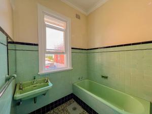 a bathroom with a green tub and a sink at Commercial Hotel Bega in Bega +10 photos
