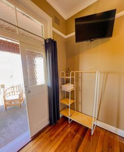 a room with a tv on the wall and a door at Commercial Hotel Bega in Bega