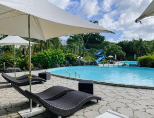 duas cadeiras e um guarda-sol junto a uma piscina em Hotel Nikko Guam em Tumon