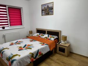 a bedroom with a bed with an orange comforter at Apartament Elena in Sibiu