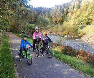 3 personnes voyageant à vélo sur un chemin à côté d'une rivière dans l'établissement Wypoczynek w górach, à Węgierska Górka