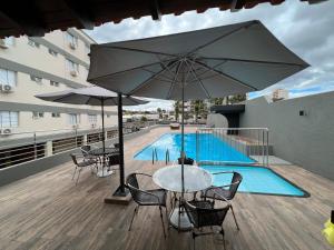 a patio with a table and chairs and an umbrella at Ônix Hotel in Assis