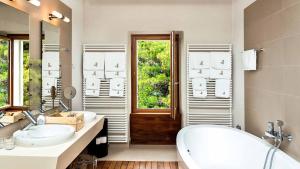 a bathroom with two sinks and a tub and a window at A beachfront villa near Omiš with a sauna and a gym in Lokva Rogoznica +21 photos