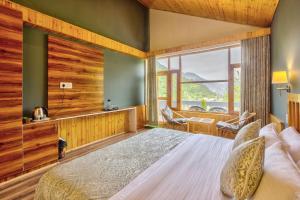 a bedroom with a bed and a large window at Doris Mountain Cabins Tirthan in Banjār