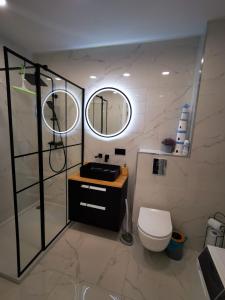 a bathroom with a toilet and two mirrors at Akacjowy Apartament in Sianozety