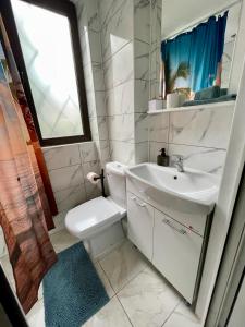 baño con lavabo y aseo y ventana en Vis-a-Vis Studio - Gara de Nord, en Bucarest