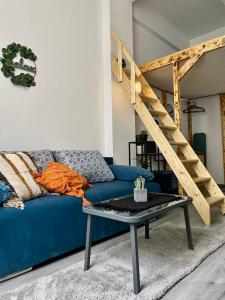 a blue couch in a living room with a ladder at Vis-a-Vis Studio - Gara de Nord in Bucharest