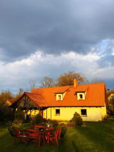 una casa de techo naranja con mesas de picnic delante de ella en Terra Natangia, en Górowo Iławeckie
