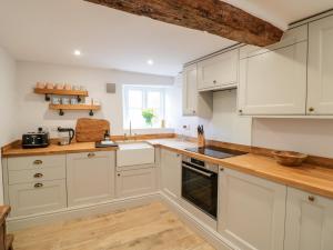 a kitchen with white cabinets and a wooden floor at Ashton House in Moreton in Marsh