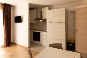 a kitchen with white cabinets and a table with chairs at MARIS Apartments & Bedrooms in Alghero