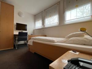 a bedroom with two beds and a desk with a telephone at Hotel Kaufhold - Haus der Handweberei in Waltrop