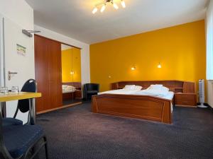 une chambre d'hôtel avec un lit et un mur jaune dans l'établissement Hotel Kaufhold - Haus der Handweberei, à Waltrop