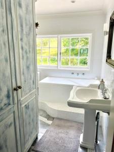 a white bathroom with a tub and a sink at Entire Bowral Acreage in Bowral